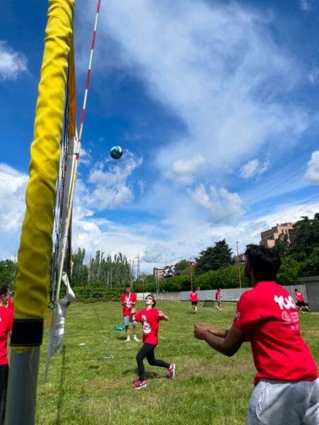 Studenți internaționali jucând volei în aer liber într-o zi senină la Milano, în cadrul unui eveniment organizat de universitate